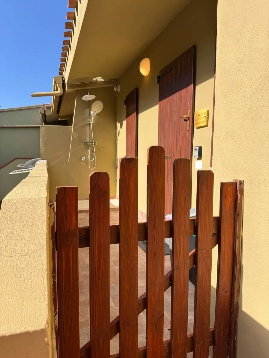 Ingresso esterno della suite: cancelletto privato in legno, smart lock keypad Grifema per self check-in 24/7, doccia esterna per il rientro dalla spiaggia.