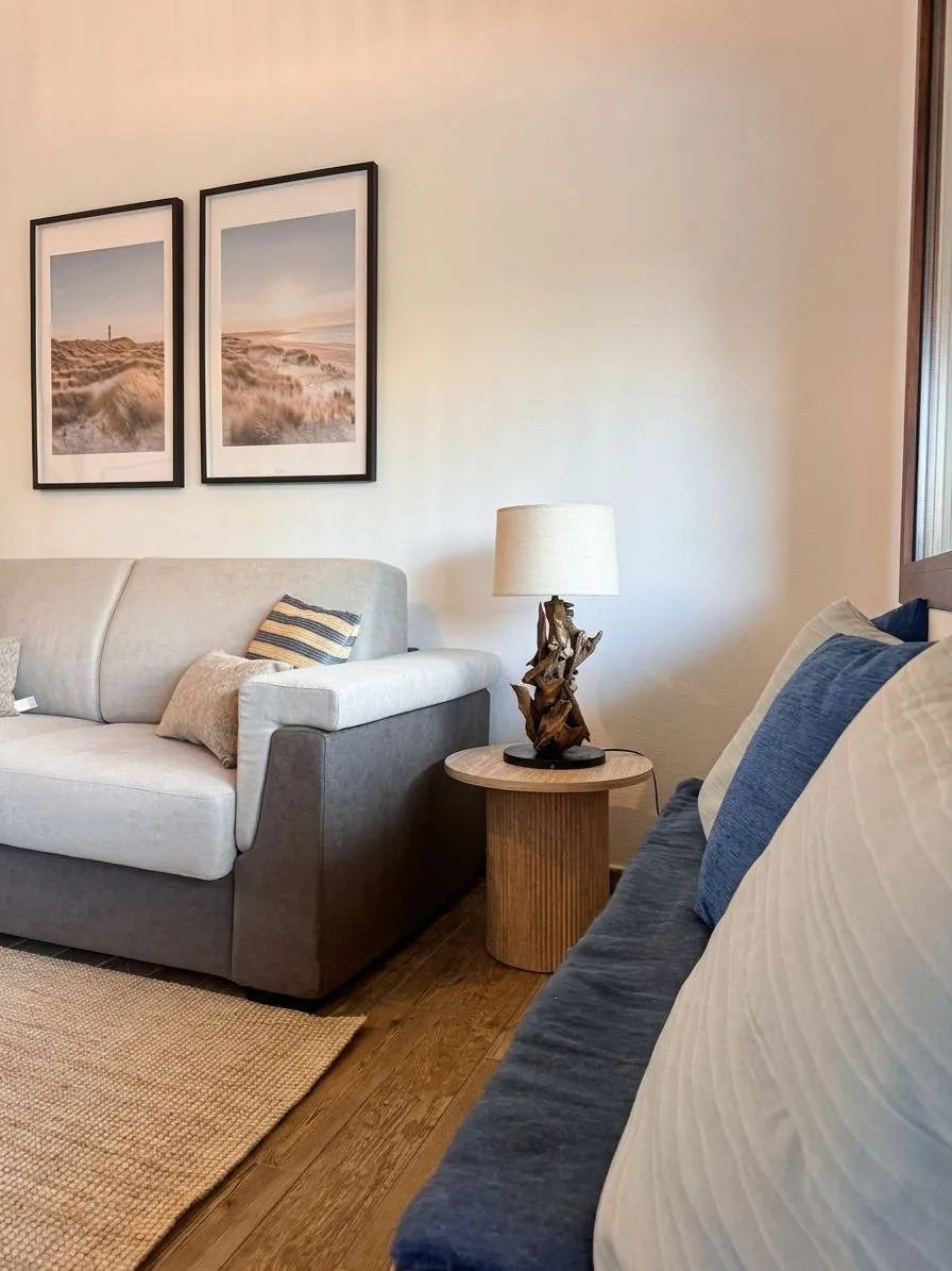 Soggiorno della suite a Cagliari con divano principale, secondo divano-letto per ospiti extra, stampe coastal con dune mediterranee, design boutique mediterraneo.