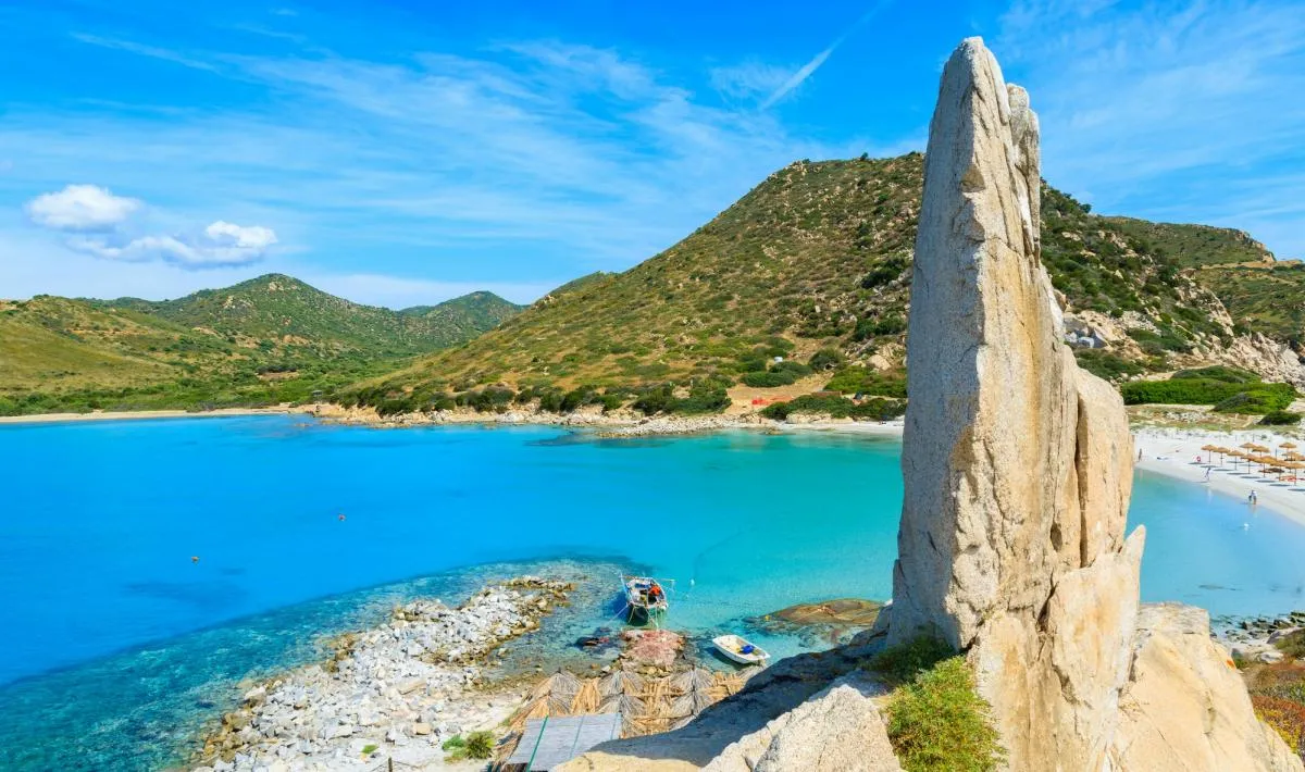 Punta Molentis a Villasimius, Sardegna: lingua di sabbia bianca finissima tra rocce di granito modellate dal vento, mare cristallino su entrambi i lati.