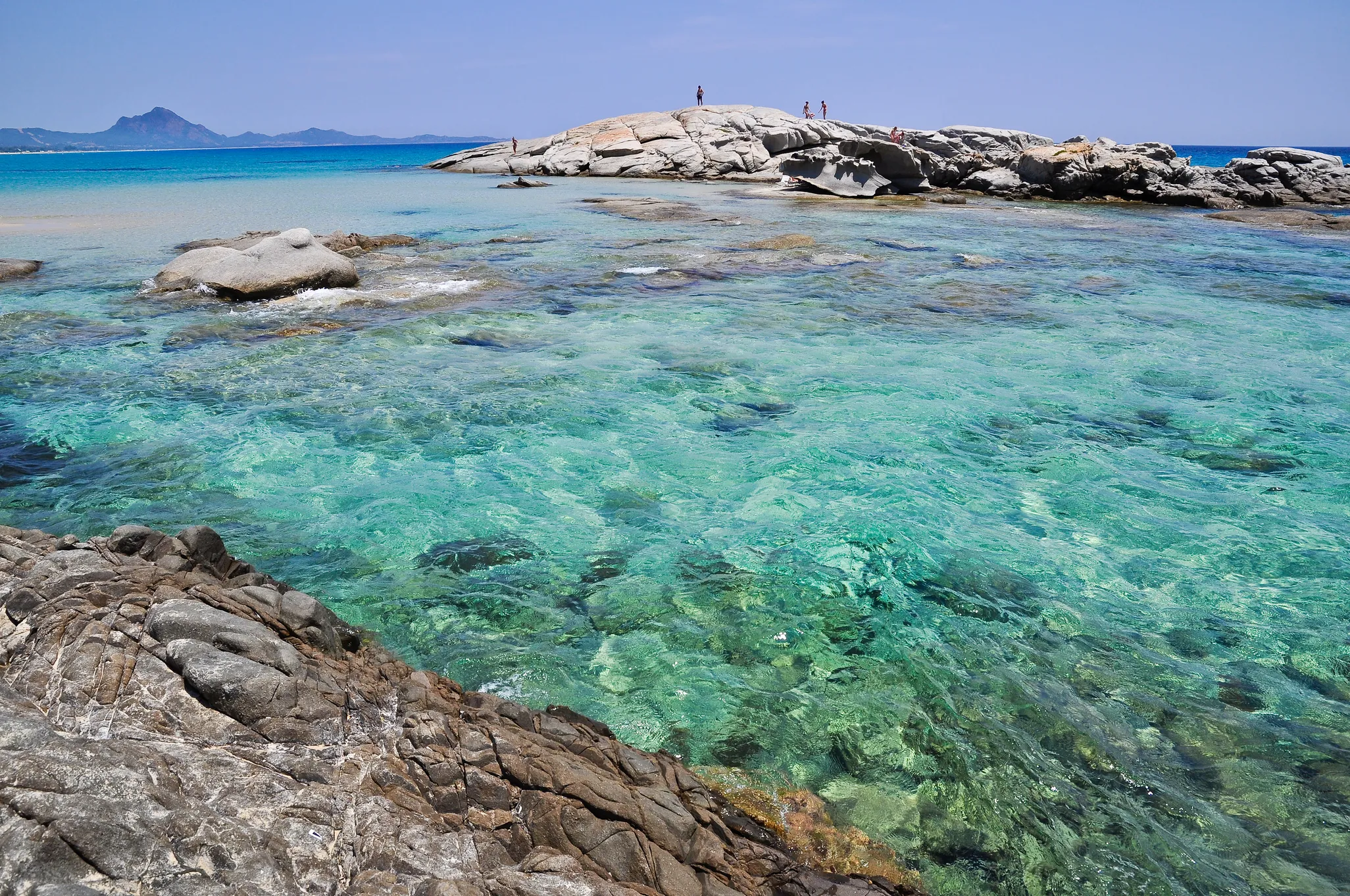 Lo Scoglio di Peppino a Costa Rei, Sardegna: distesa di sabbia bianca con fondali bassissimi dominata dalla celebre roccia piatta di granito, simbolo della costa sud-orientale.